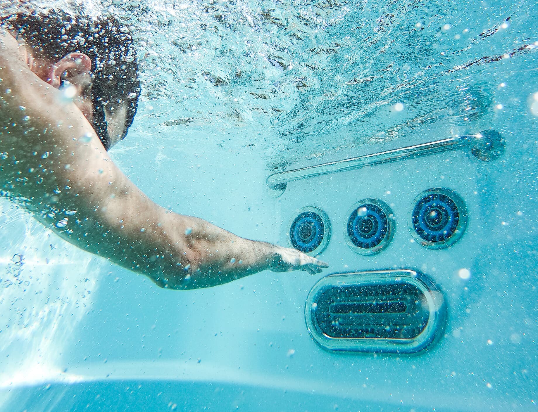 Man simmar under vattnet mot ett simaggregat i ett swimspa
